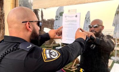שוטר מדביק צו סגירה על חלון המסעדה. צילום: משטרה