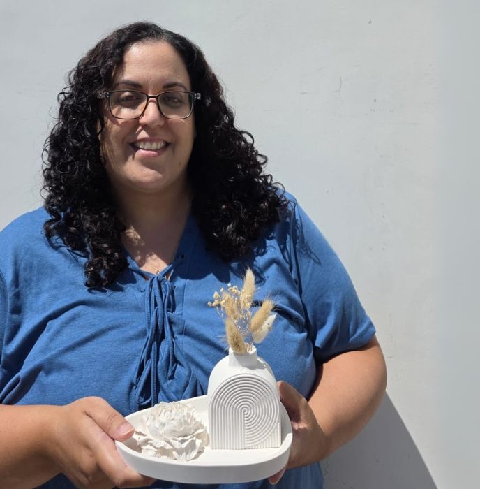 טל ברקו בחולצה כחולה מחזיקה את עבודותיה, צילום פרטי